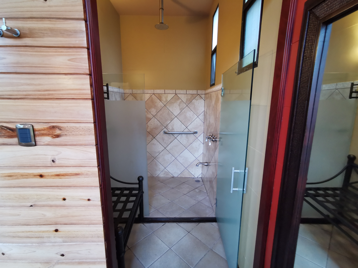 Bathroom with tiled walls, glass shower enclosure, and wooden door.