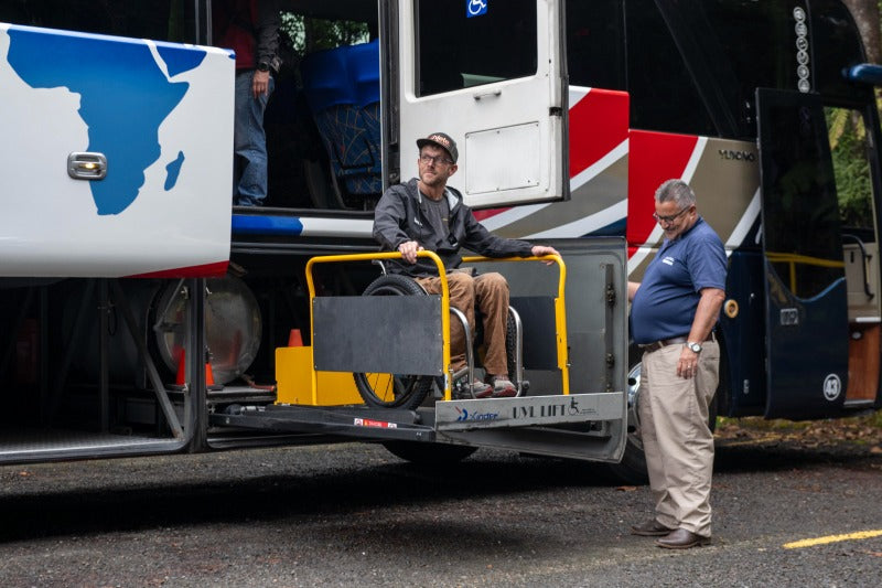 A person riding a wheelchair lift on a bus.