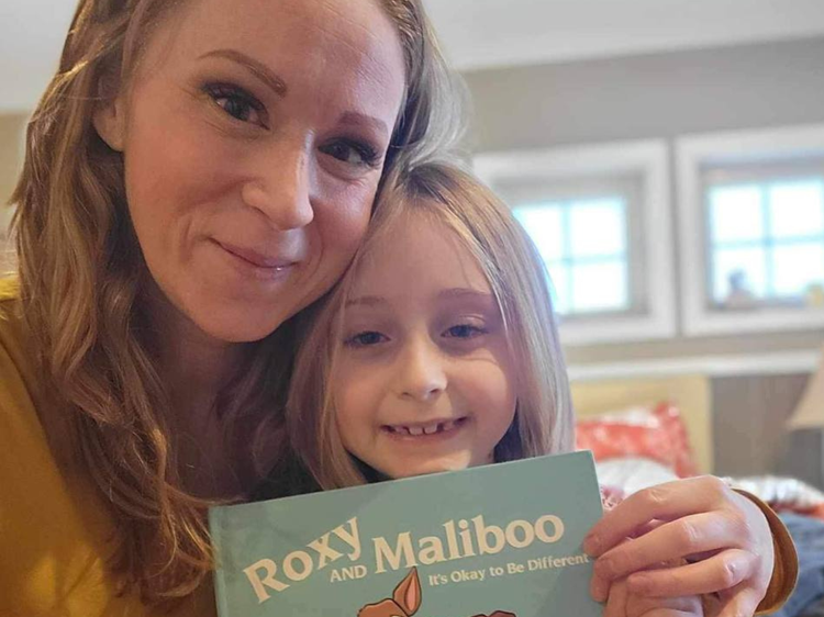Woman and child holding the Roxy and Maliboo book in a home setting.