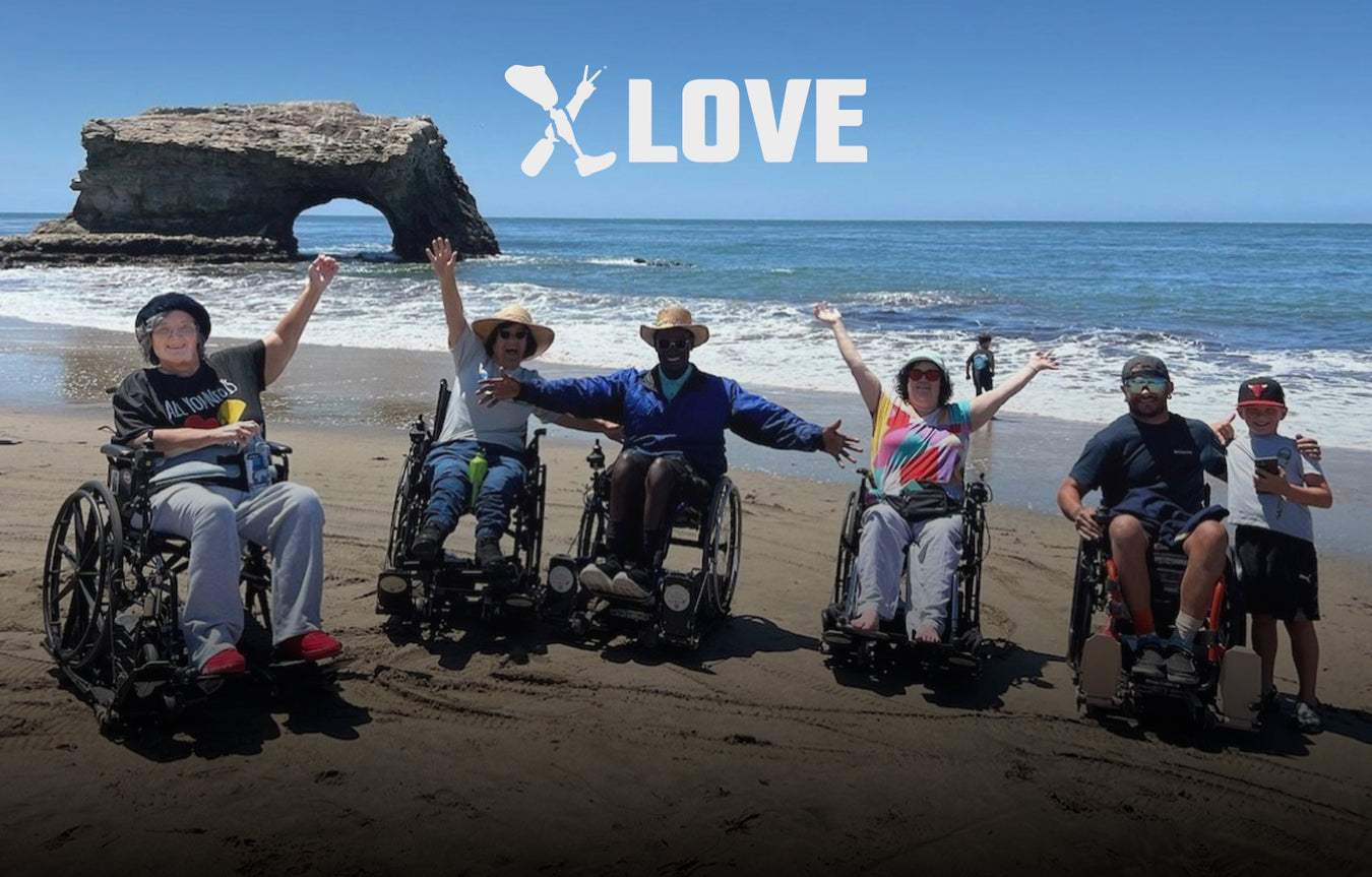 Four NorCal SCI members enjoying Natural Bridges Beach on their manual wheelchairs on top of a Freedom Trax on the sand.