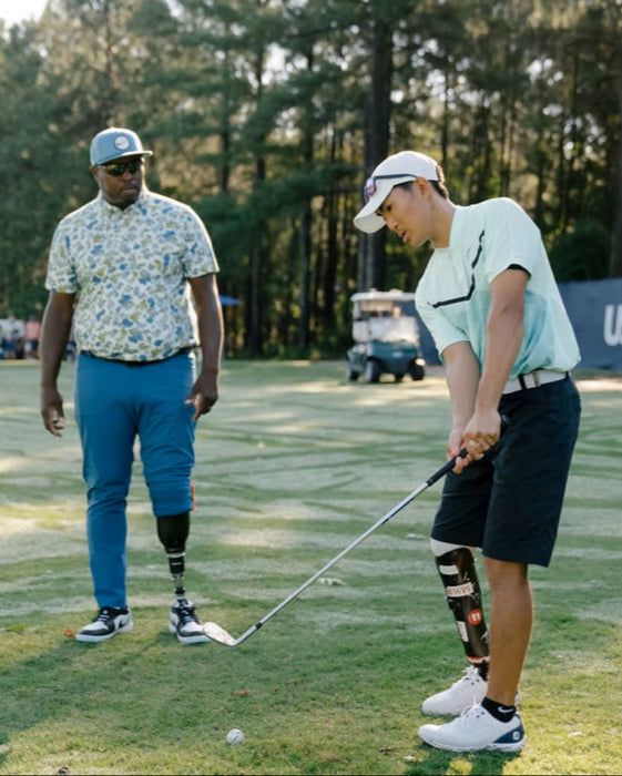 Carlos Brown coaching a golfer with a below knee amputation.