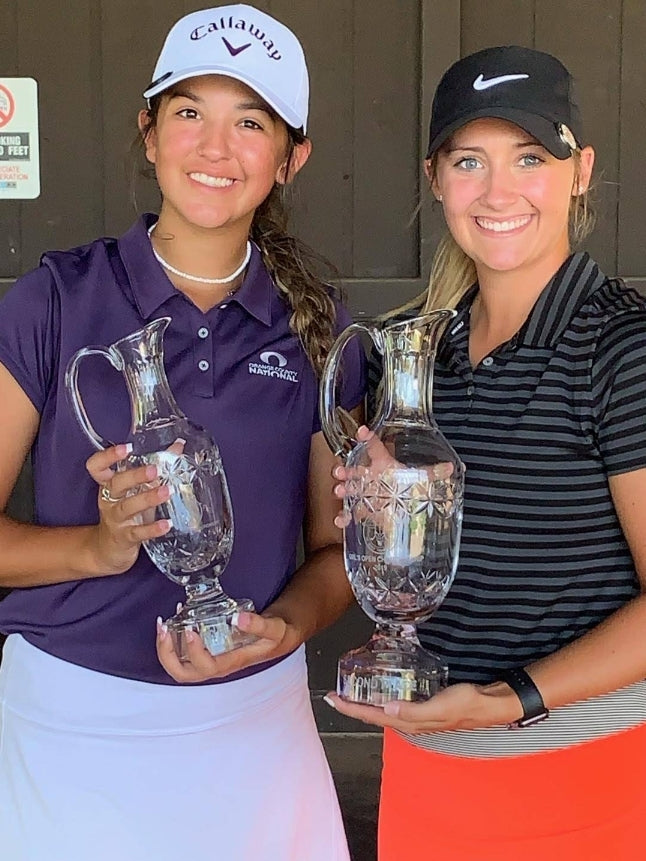 Two golfers holding trophies after being coached by Carlos Brown.