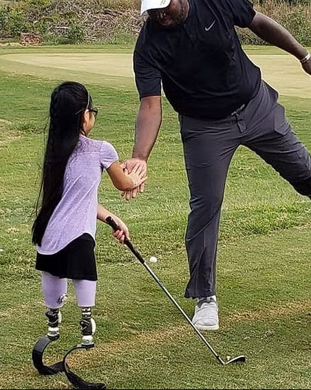 Carlos Brown high fiving a kid golfer with a double below knee amputation.
