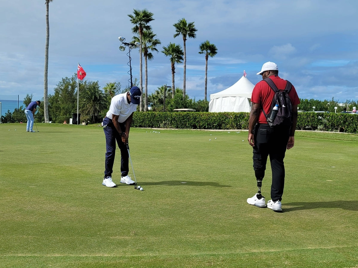 Carlos Brown coaching a golf pro at a driving range.