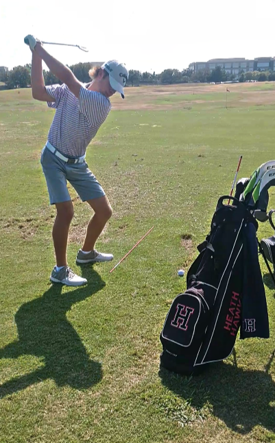 Golfer coached by Carlos Brown chipping in a row at the driving range.
