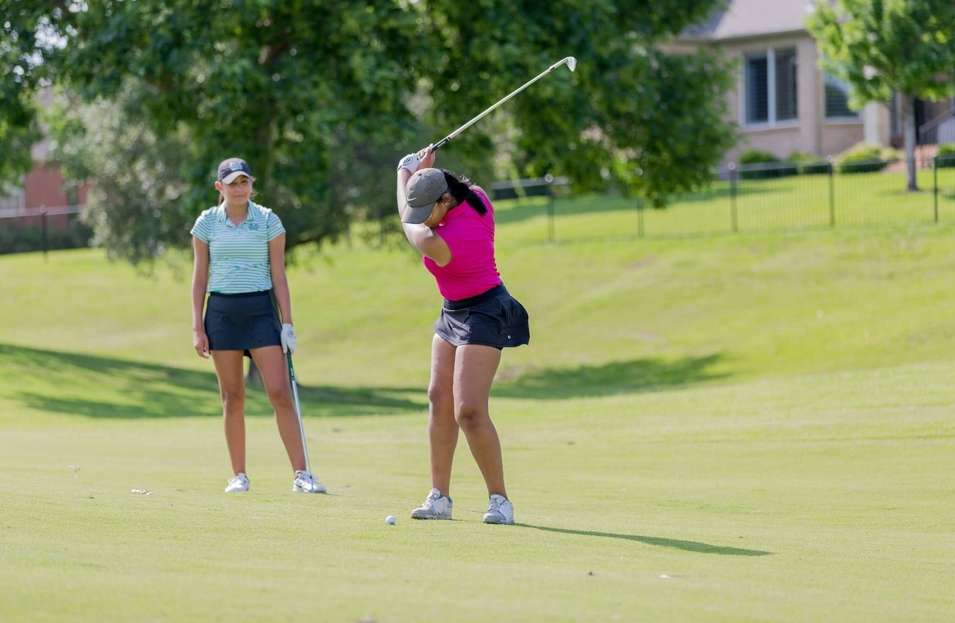 Two golfers coached by Carlos Brown on the driving range.
