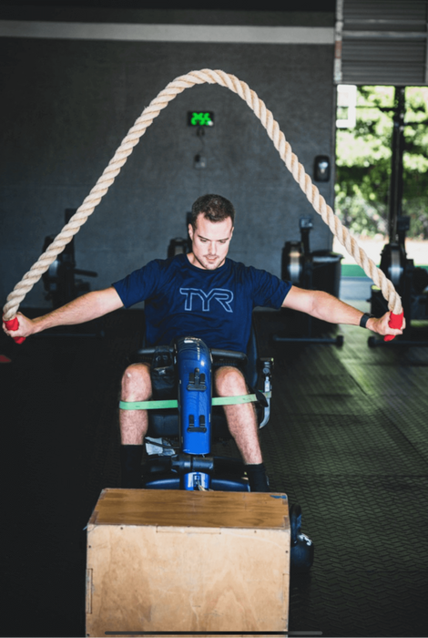 An athlete using a scooter while using the Equip Products Monster Ropes in the gym.