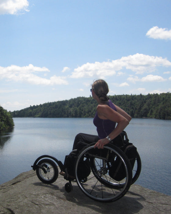 FreeWheel Wheelchair Attachment user overlooking a river from an elevated rock.
