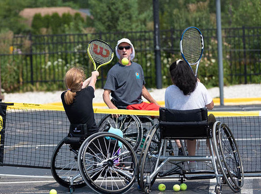Two GLASA youth wheelchair tennis athletes practicing with their coach.