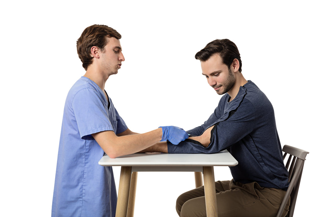 Person receiving an injection from a nurse while wearing the MAI We Care Adaptive Long Sleeve T-Shirt with the forearm of the sleeve unbuttoned allowing access for the needle