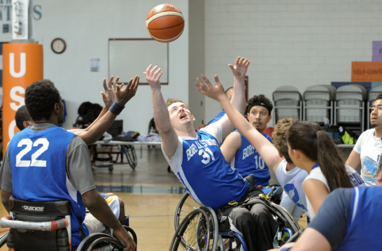 Wheelchair basketball athletes fighting for the ball in the air.
