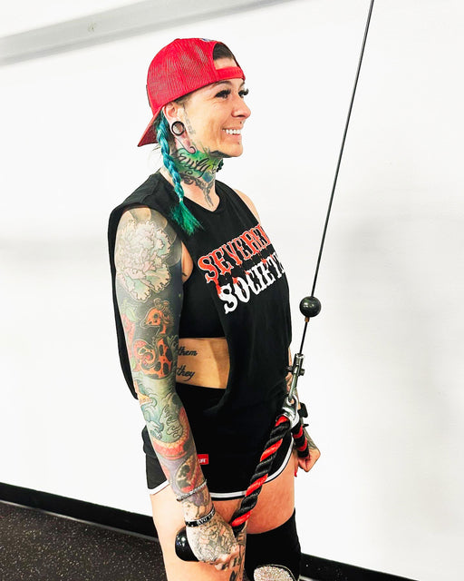 SuZanne Jacobsen smiling while performing a tricep pull down and wearing the Severed Society® Drip T-Shirt.