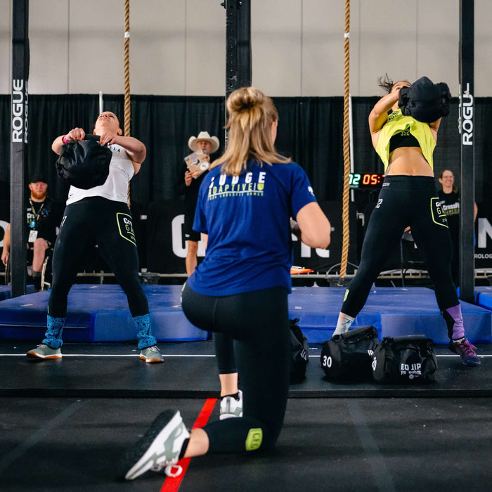 Equip Products Strongman Throw Bag being thrown in competition by two athletes with a referee watching.