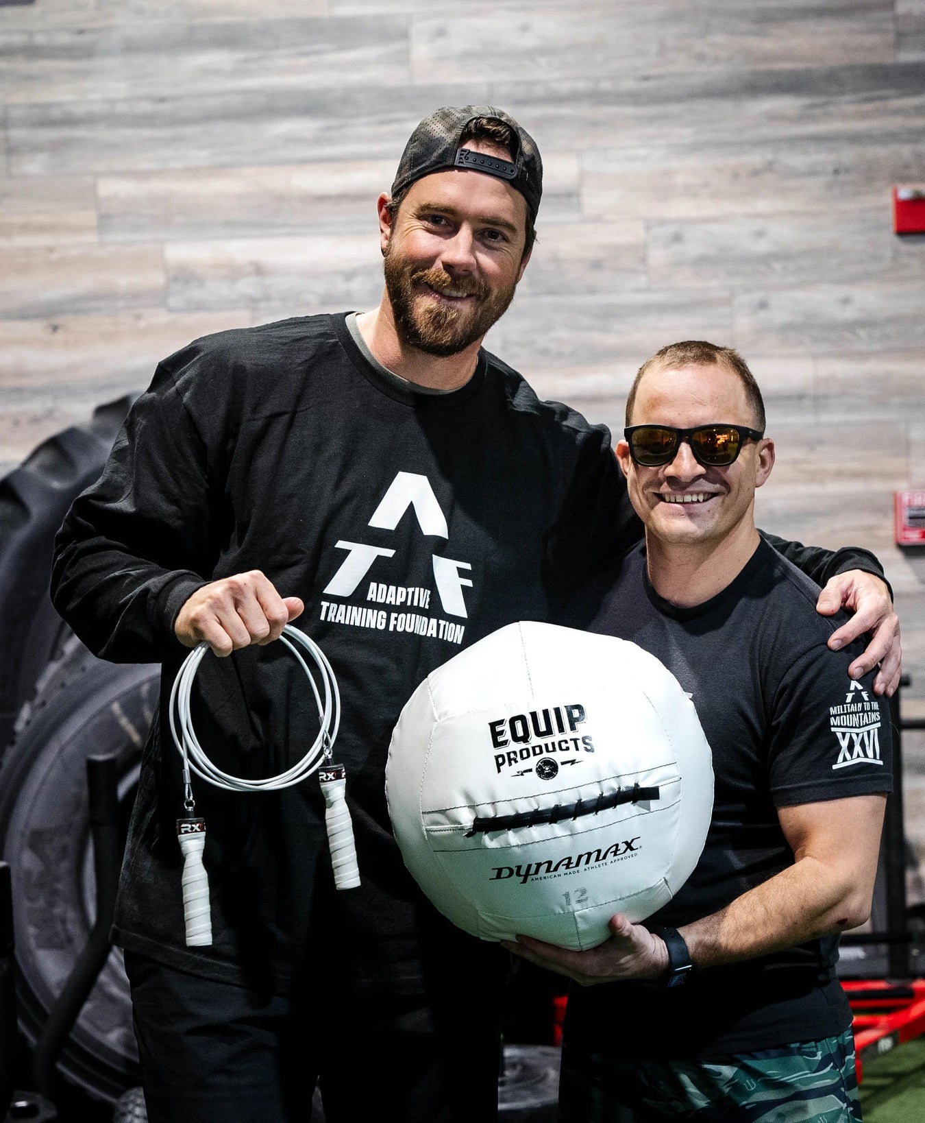 A CrossFitter with a visual impairment holding Equip Products jump rope and medicine ball with their training partner.