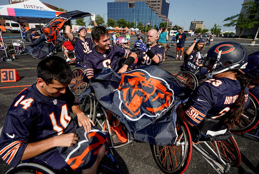 Chicago Bears Wheelchair Football team holding a Chicago Bears flag.