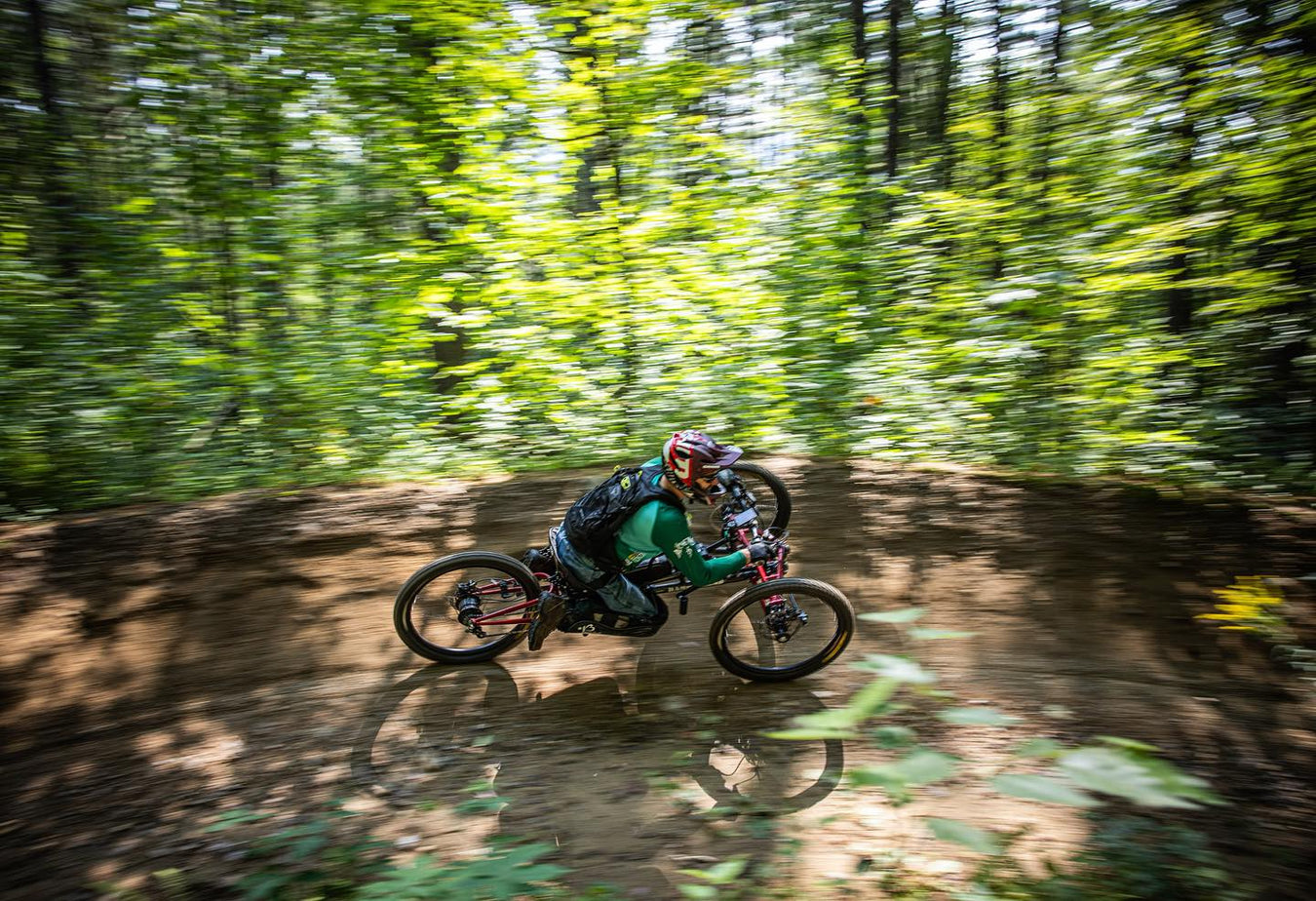 Person riding a an adaptive mountain bike on a trail through a forest
