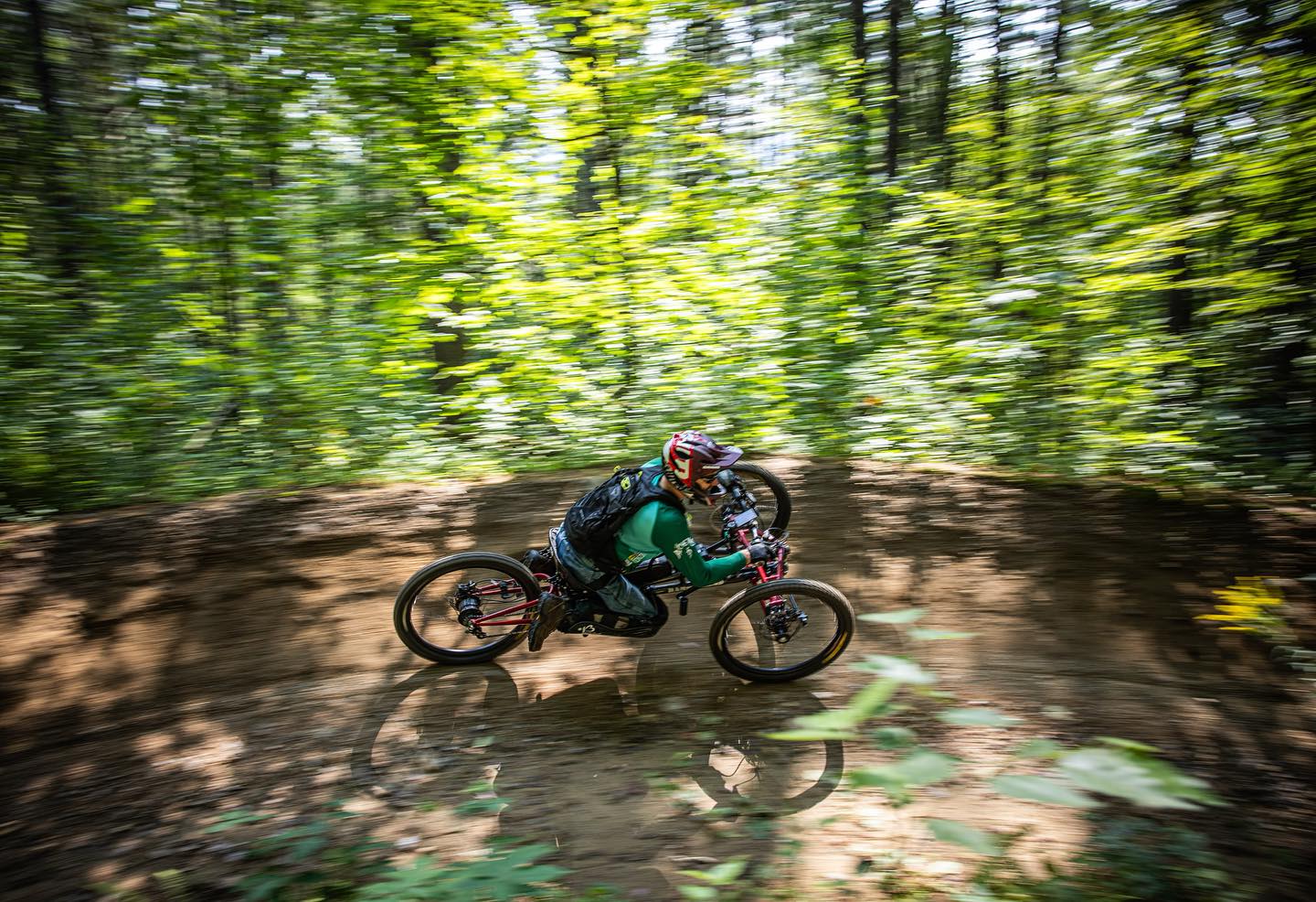 Person riding a an adaptive mountain bike on a trail through a forest