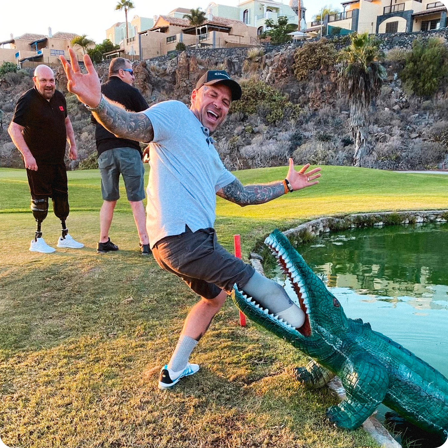 Team Amplife® Ambassador Ben Lovell posing with a large crocodile as if it's bitten off his amputated leg on a golf course