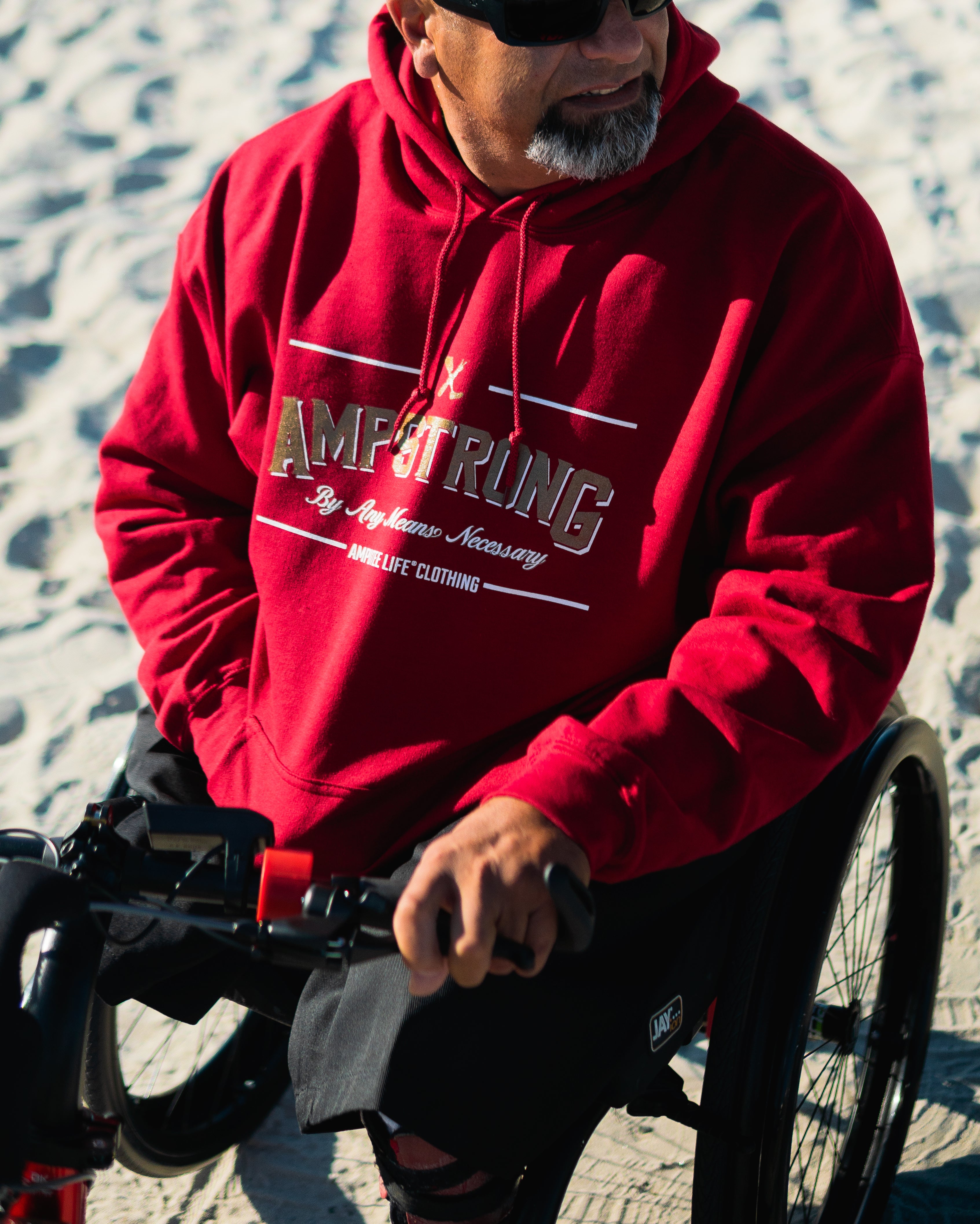 Detail of Amplife® Founder Abdul Nevarez wearing the Ampstrong Hoodie while riding the Rio Mobility Firefly 2.5 on the beach.