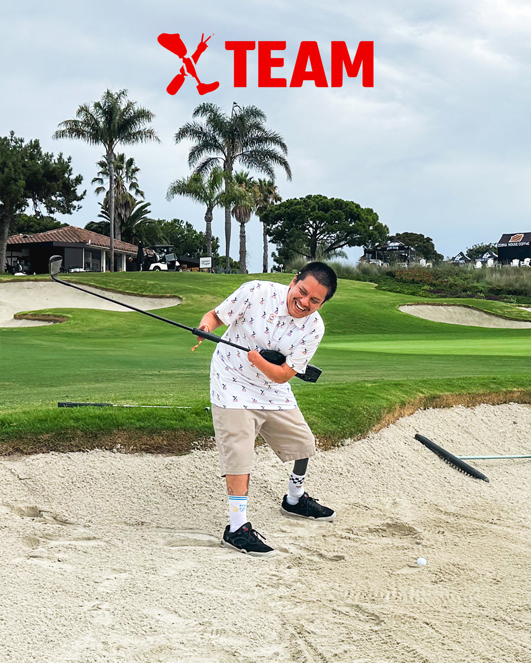 Team Amplife® Ambassador Oscar Loreto, Jr. golfing in a sand trap while laughing during his backswing.