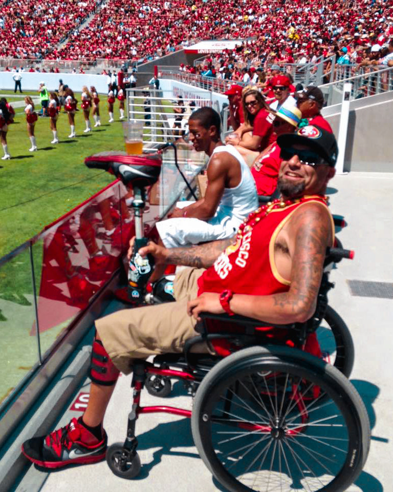 Portrait of Amplife® Foundation & Amplife® Founder Abdul Nevarez balancing a beer cup on his upright prosthetic leg at a 49ers game