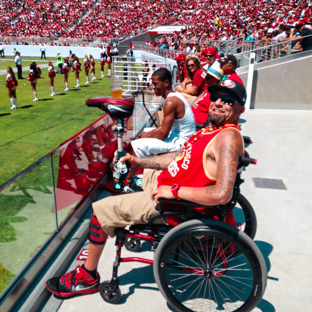 Portrait of Amplife® Foundation & Amplife® Founder Abdul Nevarez balancing a beer cup on his upright prosthetic leg at a 49ers game