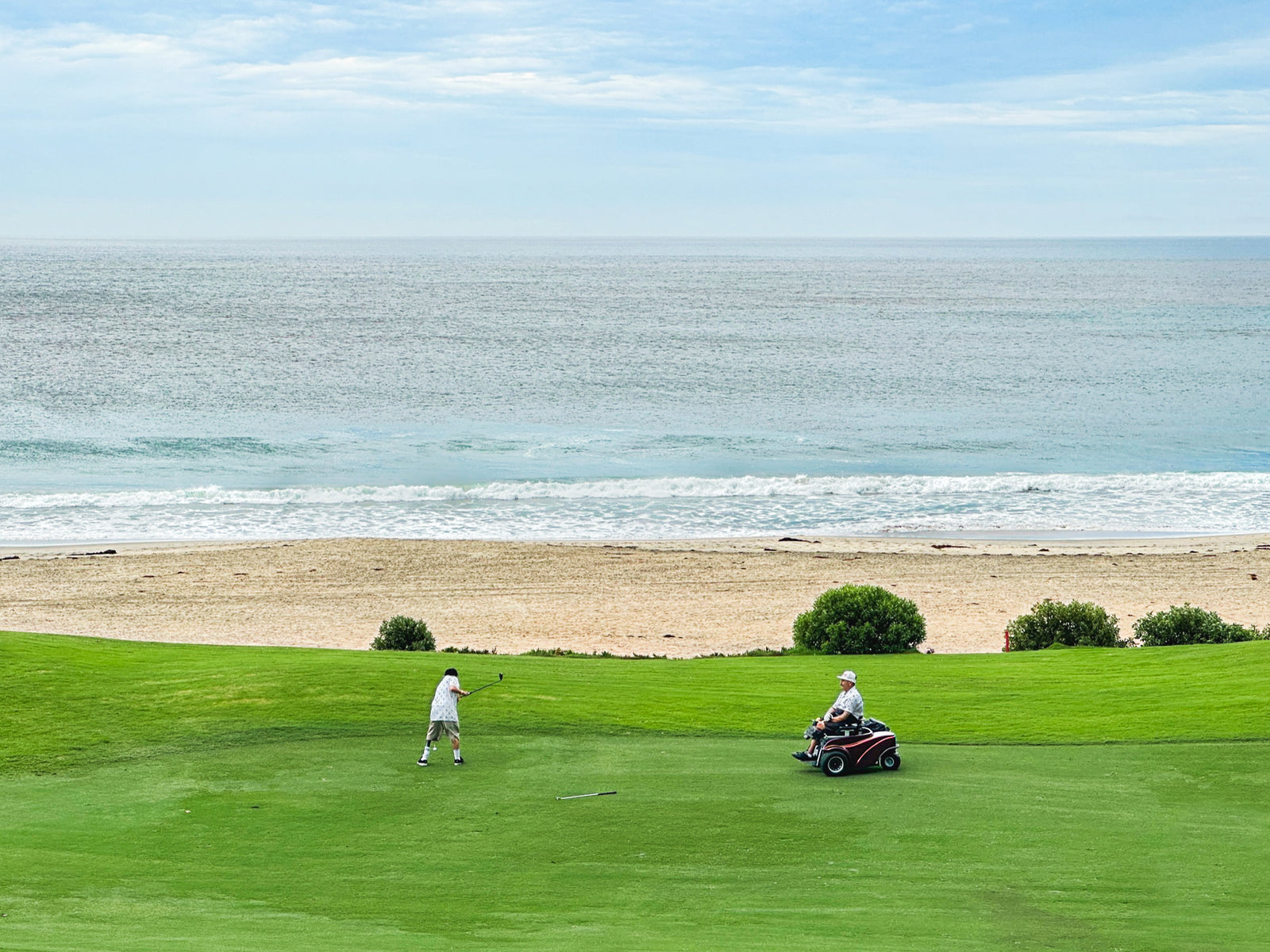 Two golfers on a coastal fairway wearing Amplife® Clothing getting ready to chip.
