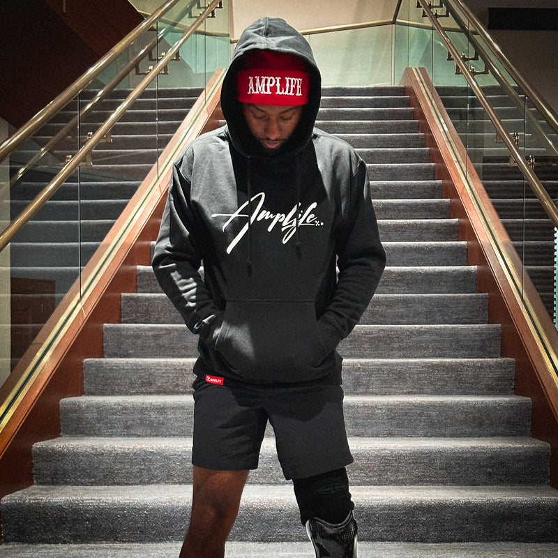 Team Amplife® Ambassador Michael Braxton Jr. wearing the Amplife® Signature Hoodie and Amplife® Beanie on a staircase.