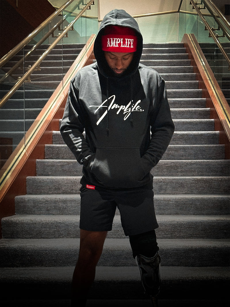 Team Amplife® Ambassador Michael Braxton Jr. wearing the Amplife® Signature Hoodie and Amplife® Beanie on a staircase.