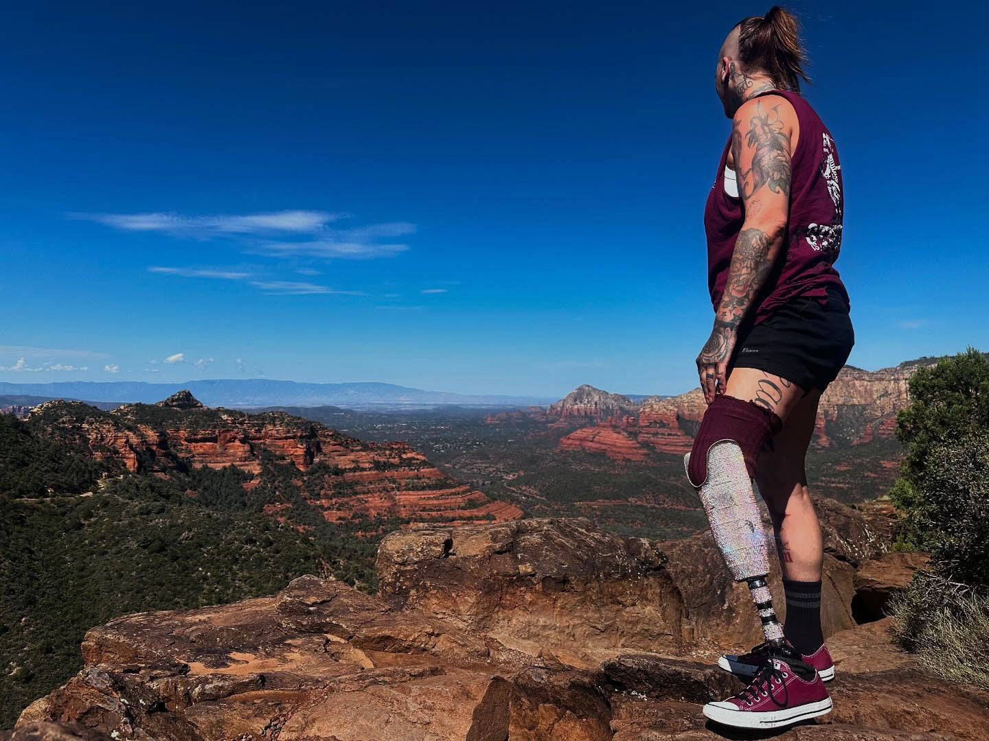 Team Amplife® Ambassador SuZanne Jacobsen standing on a rocky outcrop with a scenic landscape in the background