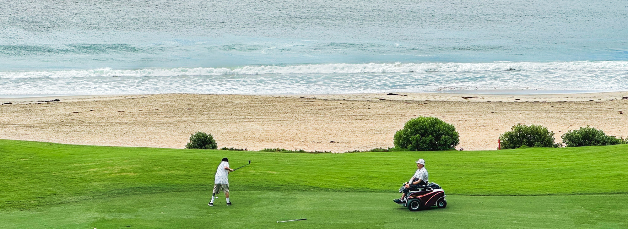 Two golfers on a coastal fairway wearing Amplife® Clothing getting ready to chip.