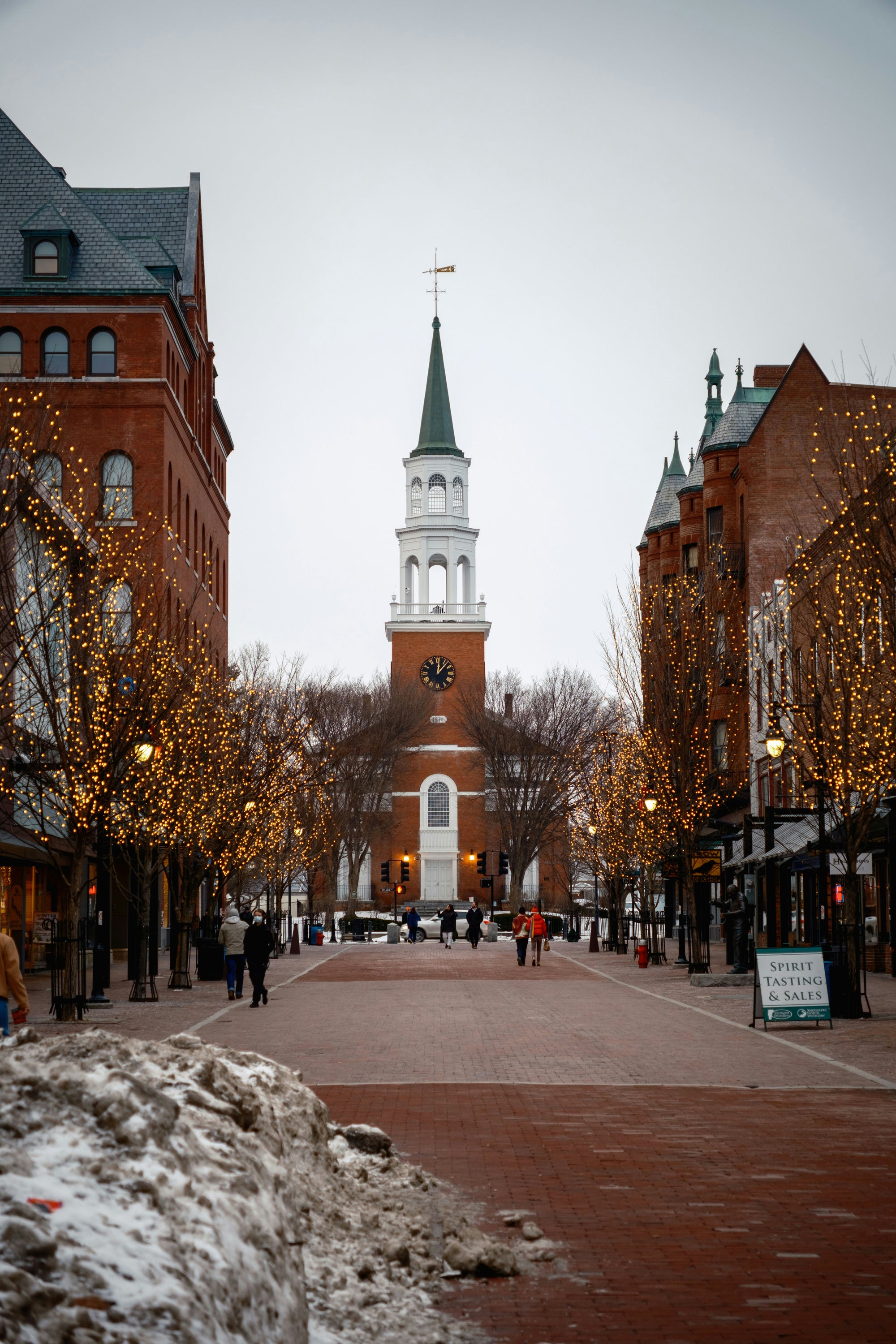 Burlington, Vermont town square with a clock tower and people walking on a snowy day