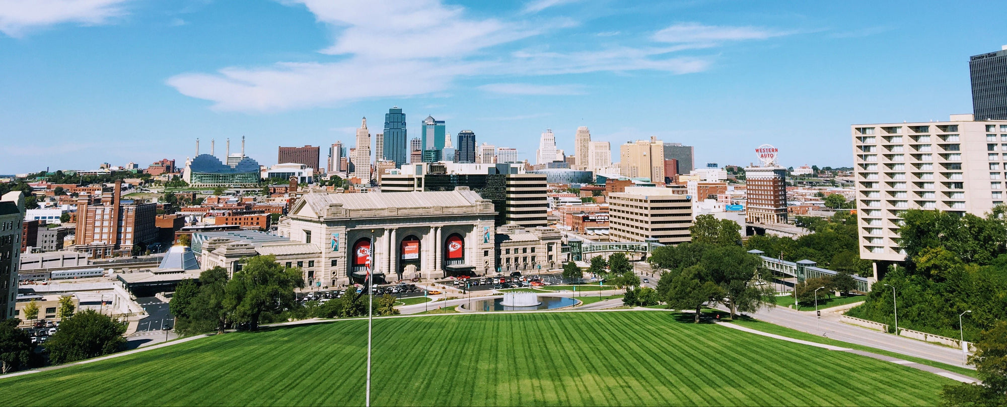 Kansas City skyline panoramic view with green foreground under clear blue sky.