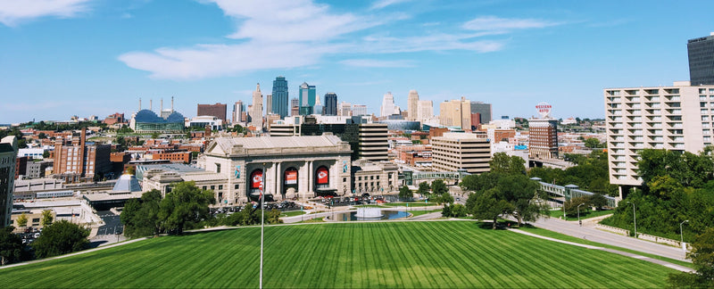 Kansas City skyline panoramic view with green foreground under clear blue sky.