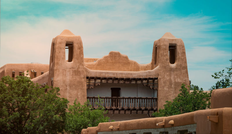 Traditional adobe-style building in Santa Fe with a blue sky and greenery