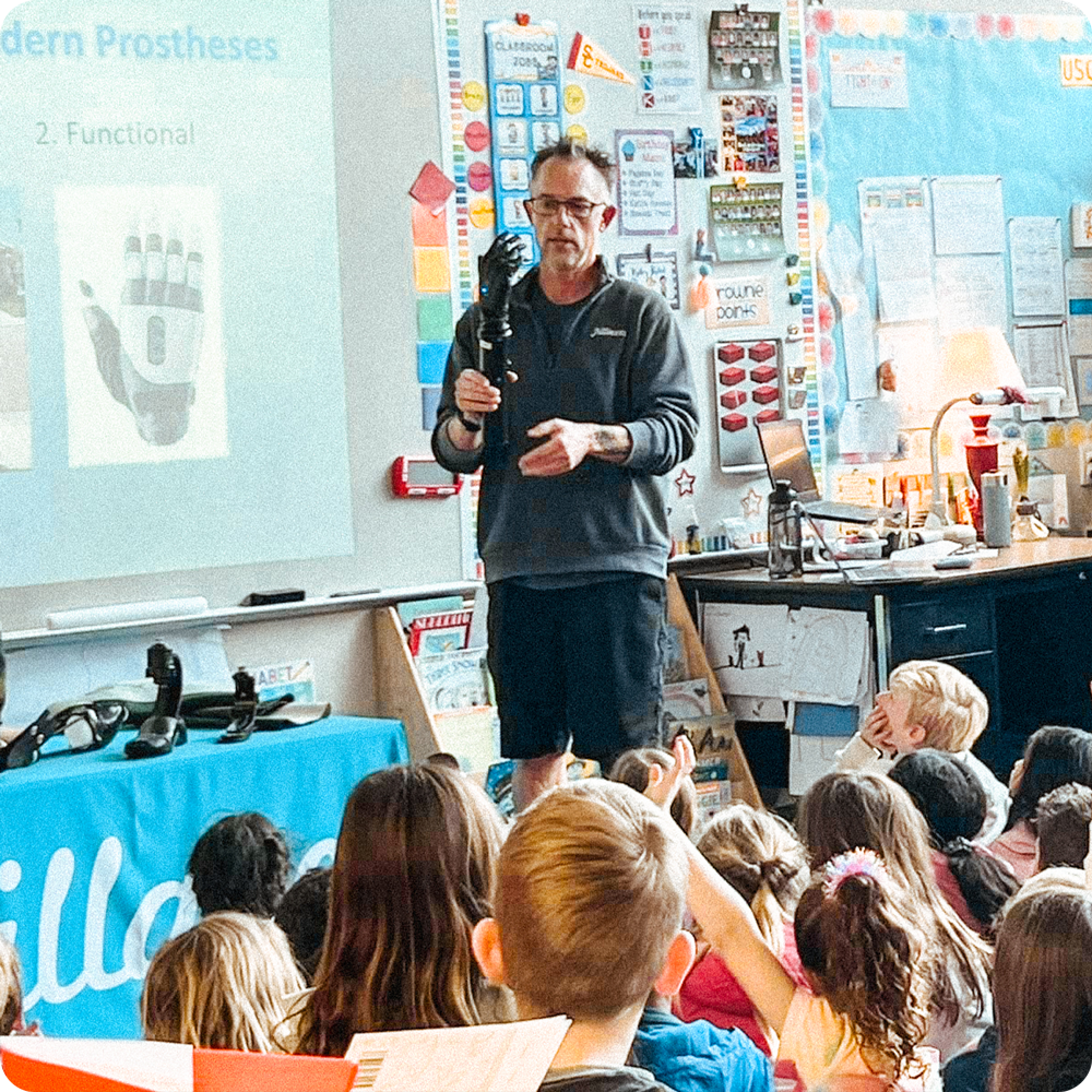 Andrew May giving a presentation to a class of students in a classroom about prosthetics.