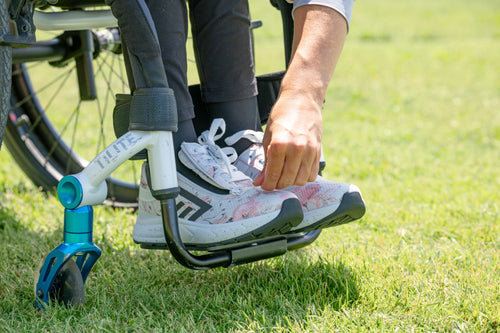 Person in a wheelchair adjusting their BILLY Sport Shoe in a park setting