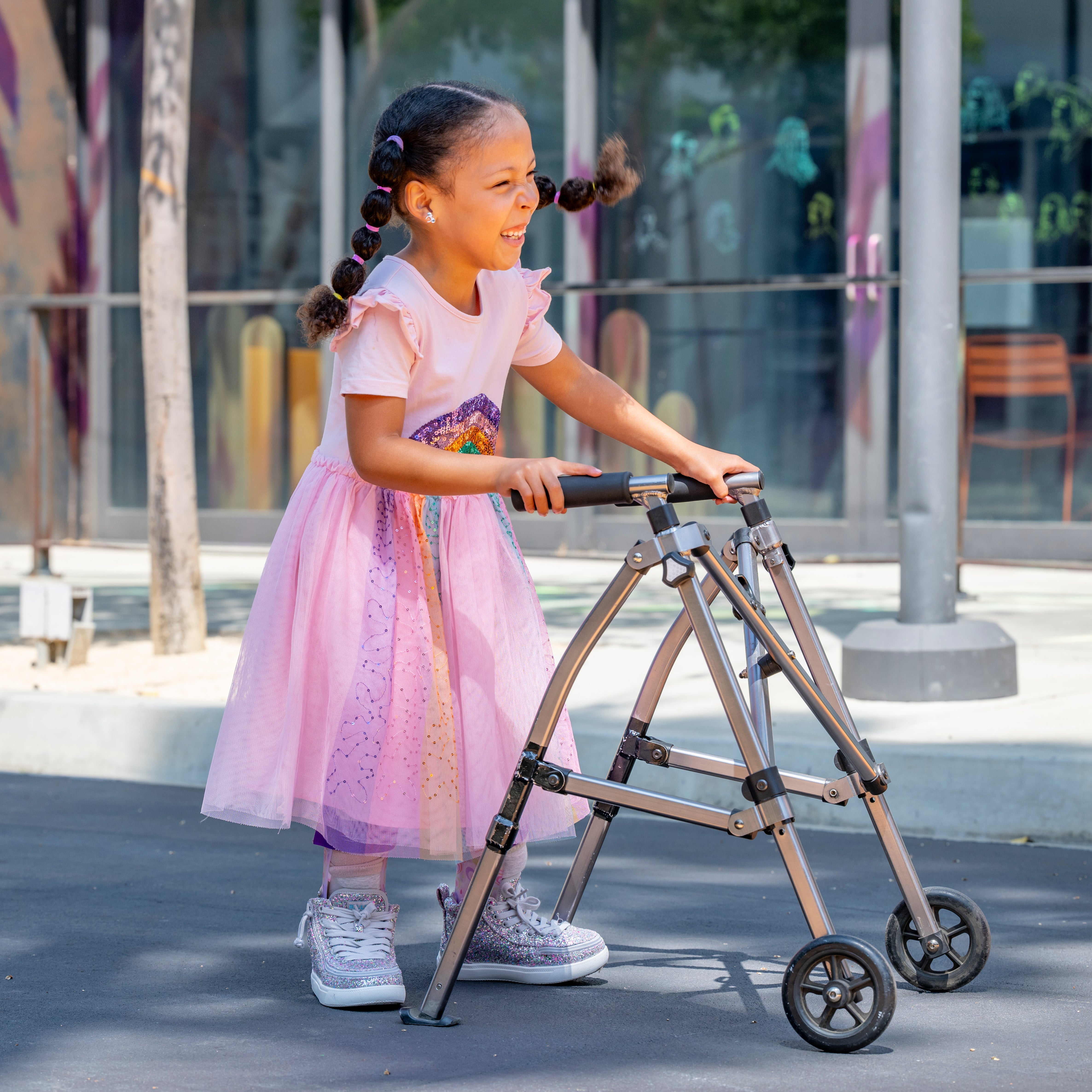 Young girl in a pink dress using a walker outdoors wearing BILLY Footwear 