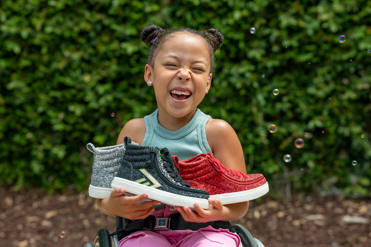 Cesily Collete smiling while holding three pairs of her collaboration with BILLY Footwear.
