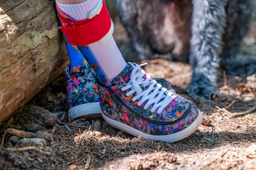Colorful patterned BILLY Footwear worn with a red AFO, standing on a natural ground.