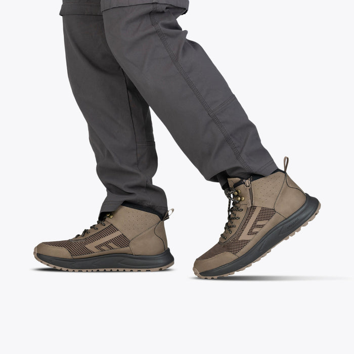 Men's Taupe BILLY Inclusion Trail Boot modeled with gray pants on a white background