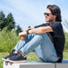 Man sitting outdoors wearing sunglasses, casual clothing and the Men's Black Leather BILLY Comfort Luxe.