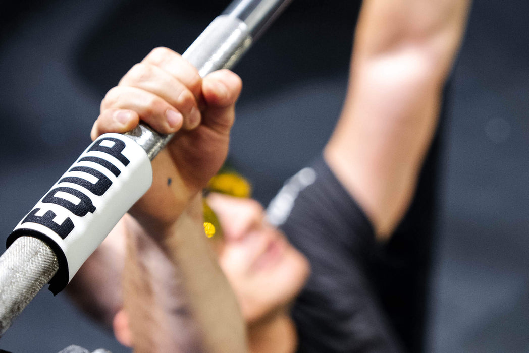 Detail of Equip Products Barbell Markers for Visually Impaired in use on a barbell as the athlete performs a bench press.