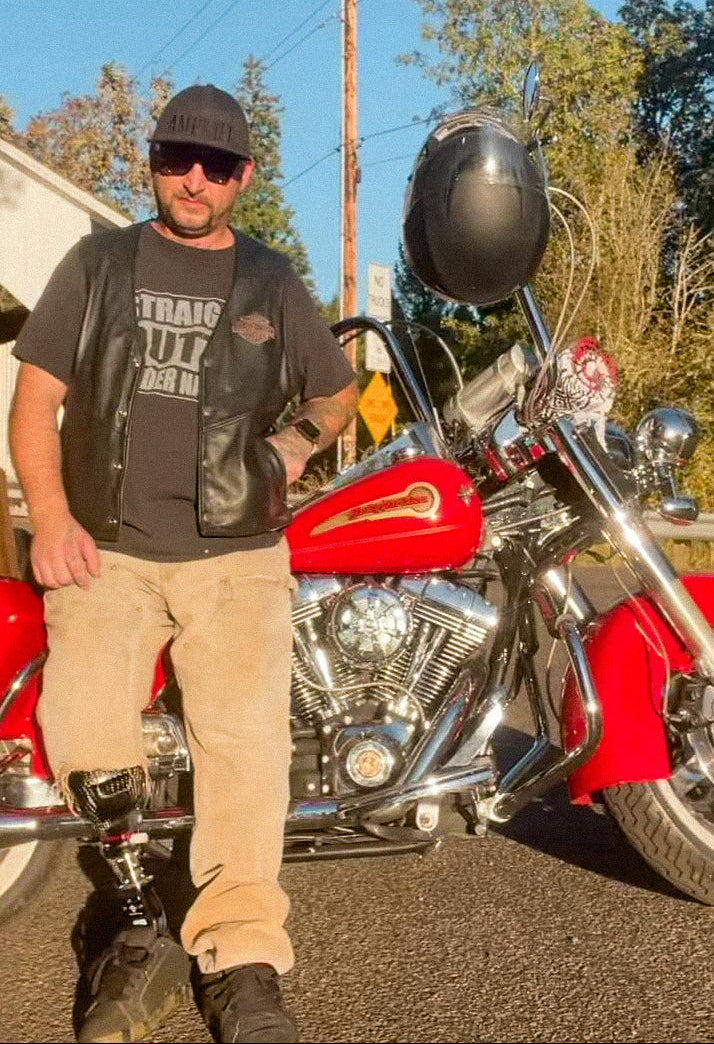 Team Amplife® Ambassador Cassidy Esty wearing the Amplife® Flat Bill Fitted standing next to his red motorcycle on a sunny day