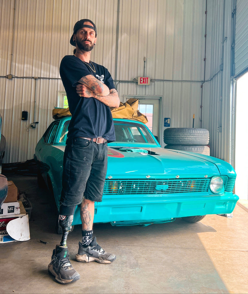 Team Amplife® Ambassador Cole Neely standing in a garage with a turquoise car 