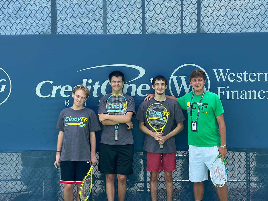 Four young tennis players standing together.