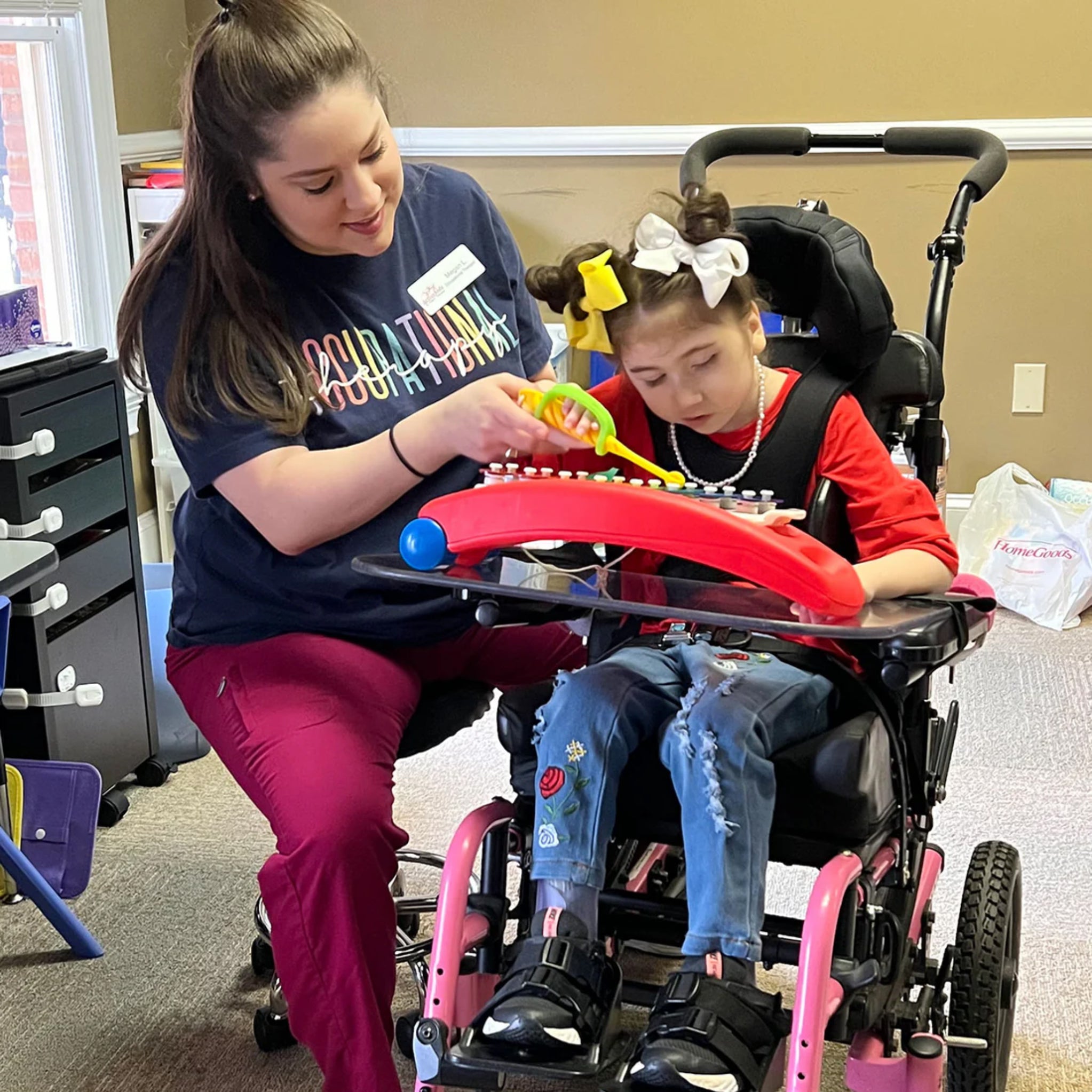 Occupational therapist assisting a child using a wheelchair with a toy in a home setting