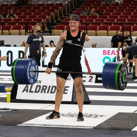 A left above the elbow amputee deadlifting 405lbs+ in a competition with the Aldridge Arm attached to the barbell and strap around the left shoulder.