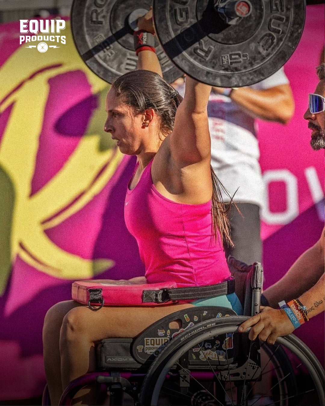 A CrossFitter using a wheelchair about to performing a shoulder press with a 10lbs on each side of the barbell in a competition.