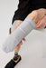 A close-up of a person seated against a white studio background, wearing a Ethnocare Underlay Transtibial Closed Prosthetic Sweat Management Device  around their residual limb. A prosthetic lower leg and black shoe are also on the other leg, along with a black shirt on the upper body.